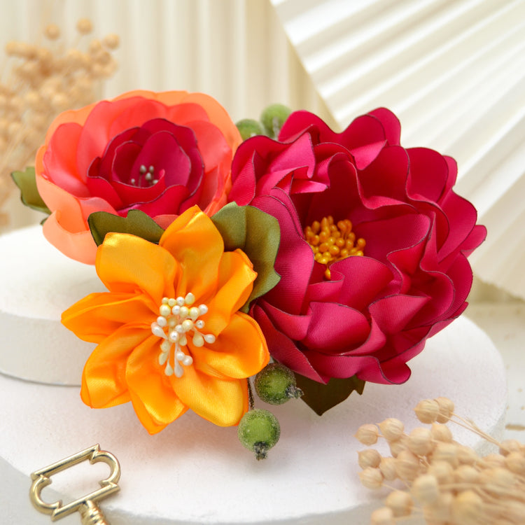 Einzigartiger Fascinator mit tropischem Flair – drei lebendige Blüten in Gelb, Pink und Koralle, umgeben von Blättern und Beeren.
