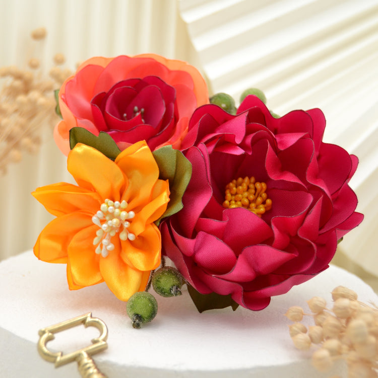 Exotischer Fascinator – Handgefertigte Blumen in Gelb, Pink und Koralle, umgeben von Blättern und grünen Beeren.