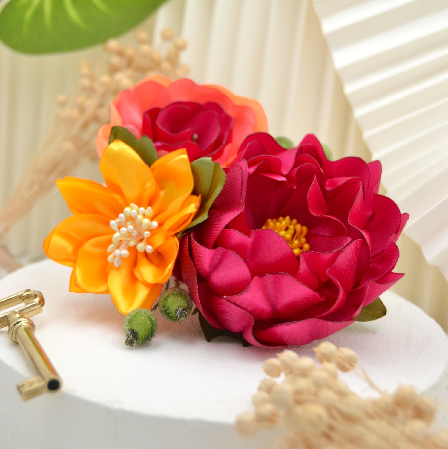 Sommerlicher Fascinator mit drei lebhaften Blumen und exotischen Details, ideal für Boho-Hochzeiten und festliche Anlässe.