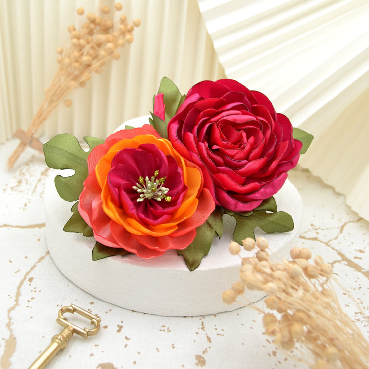 Tropisch anmutender Fascinator in Pink und Orange mit detailgetreuen Blüten und Blättern, befestigt mit einem Krokodilclip.